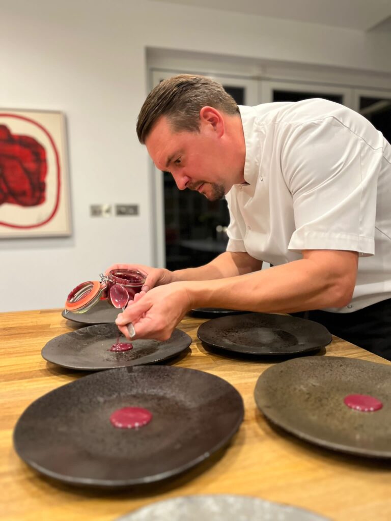 chef pouring purple sauce on to plate